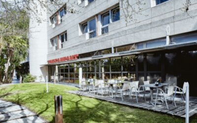 Outdoor restaurant terrace with white tables and chairs beside a landscaped lawn and modern hotel building at Hotel Best Western PLUS Alfa Aeropuerto.