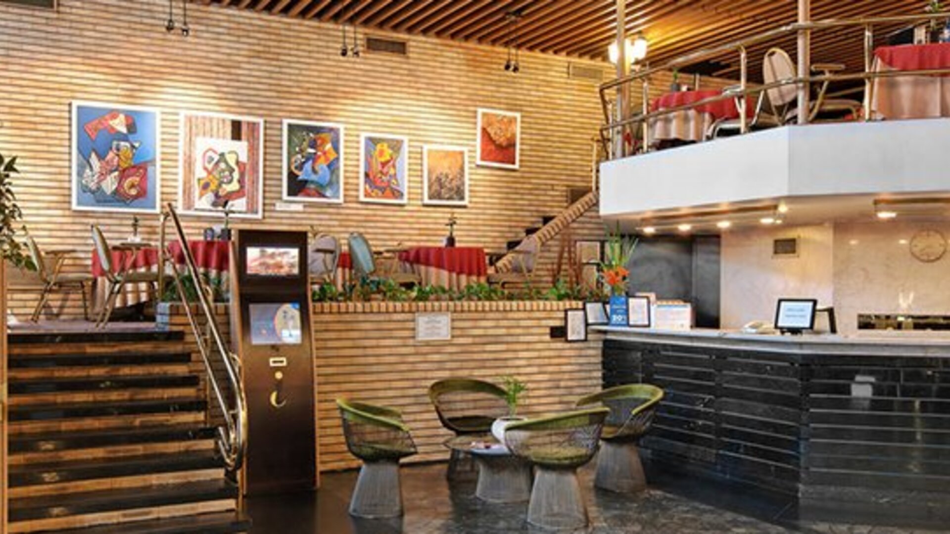 Reception area with black front desk, staircase, brick walls and small round tables with chairs at Hotel Regente Palace.