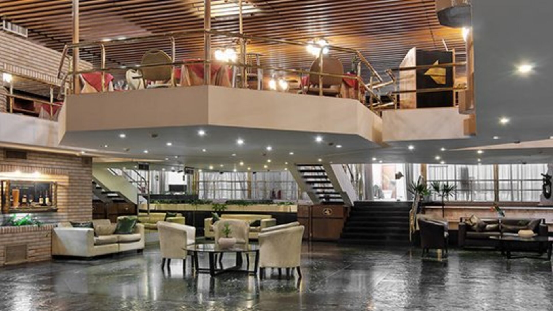 Spacious lobby with leather lounge seating, reception area, staircase and upper-level balcony at Hotel Regente Palace.