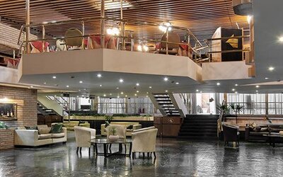 Spacious lobby with leather lounge seating, reception area, staircase and upper-level balcony at Hotel Regente Palace.
