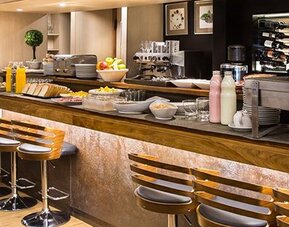 Hotel bar with long wooden counter, bar stools, illuminated bottle displays and polished wood finishes at Hotel Regente Palace.