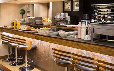 Hotel bar with long wooden counter, bar stools, illuminated bottle displays and polished wood finishes at Hotel Regente Palace.