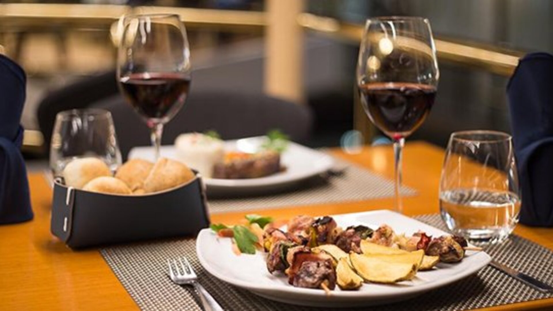 Restaurant table set with plated food, bread rolls, wine glasses and folded napkins at Hotel Regente Palace.