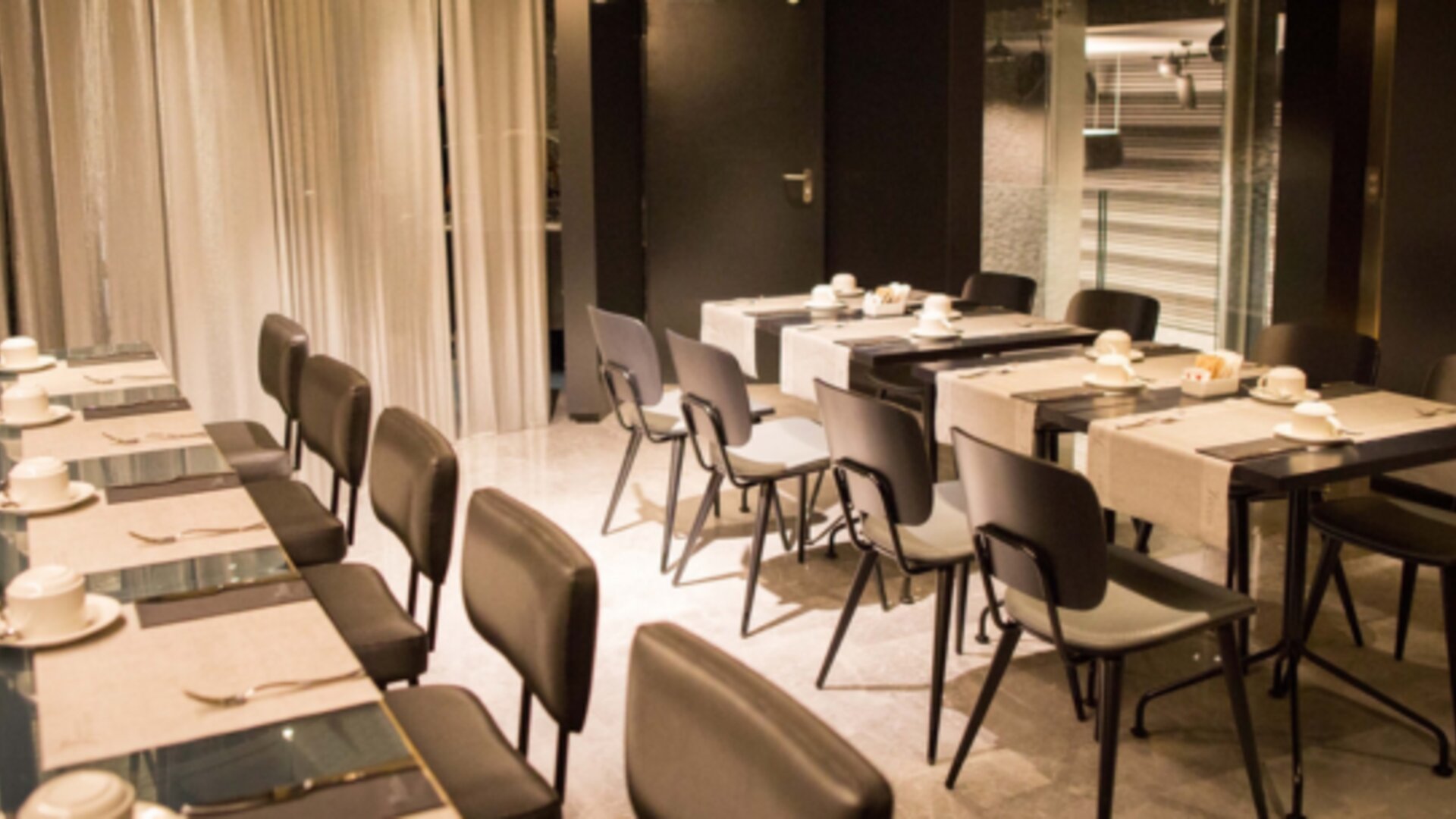 Meeting room with neatly arranged tables, dark chairs, white place settings and warm recessed lighting at Hotel Silken Saaj Las Palmas.