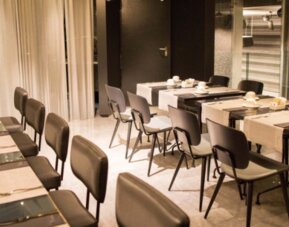 Meeting room with neatly arranged tables, dark chairs, white place settings and warm recessed lighting at Hotel Silken Saaj Las Palmas.