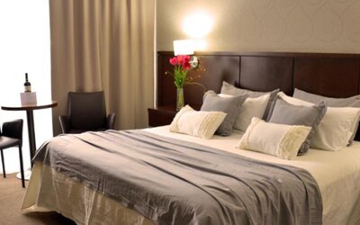Guest room with a king bed, grey runner, layered pillows, bedside tables and warm lighting at Ian Hotel.