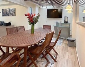 Dining area with wooden table and chairs, flower arrangement, pendant lights and staircase at 12 Nights Hotel.