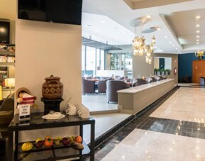 Hotel lobby with reception counter, lounge seating, decorative chandeliers and blue accent wall at Hotel Misión Toreo Centro De Convenciones.