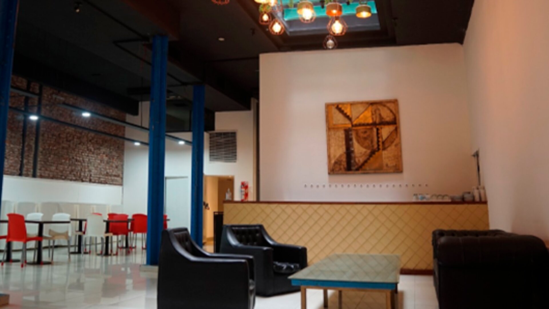 Lounge area with black sofas, low coffee table, blue support columns and colorful pendant lighting at Bagu Buenos Aires.