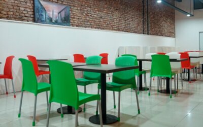 Dining area with red and green chairs, black tables, exposed brick walls and glossy tiled flooring at Bagu Buenos Aires.