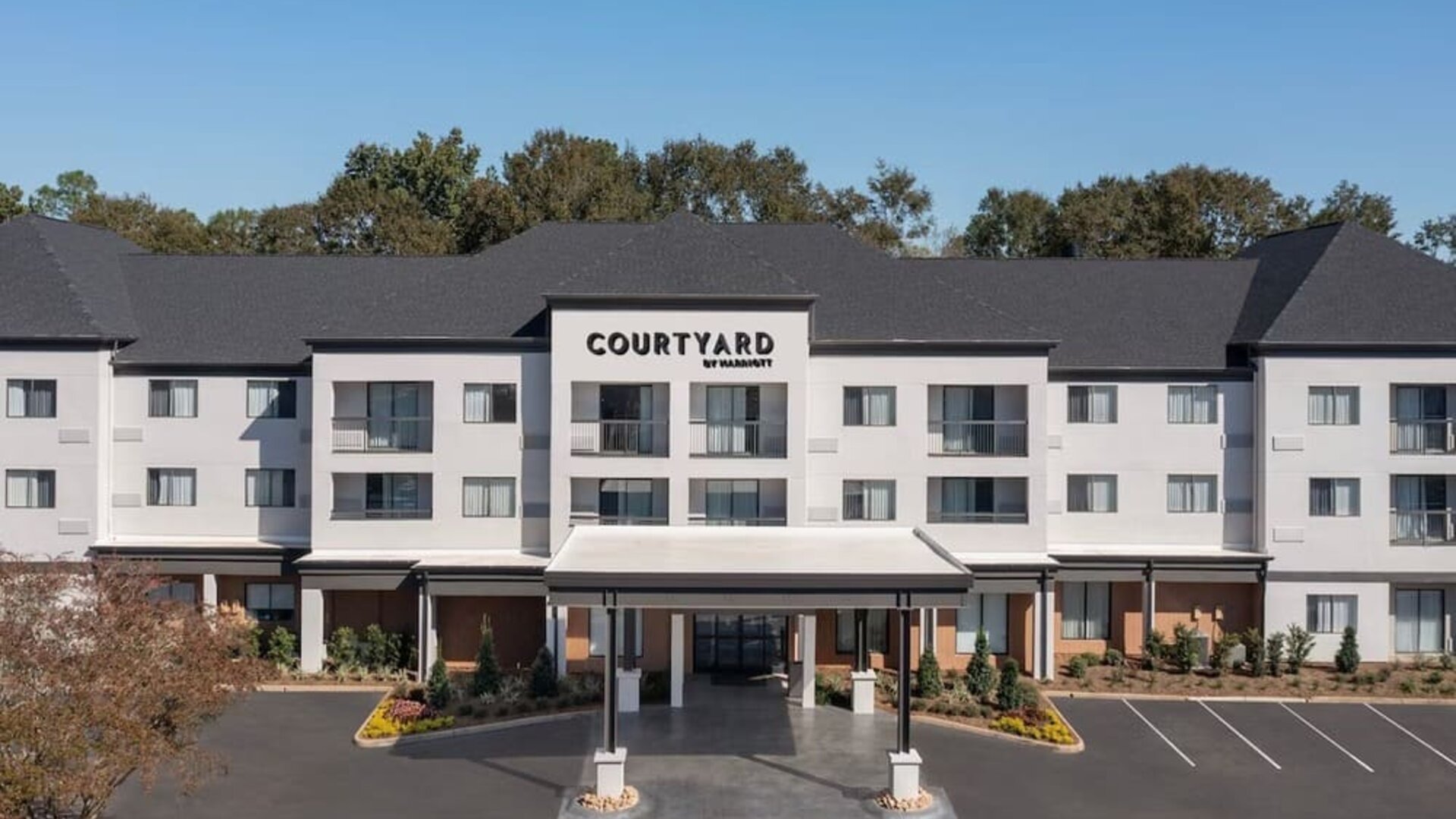 Exterior view of the Courtyard by Marriott hotel building with covered entrance, landscaped grounds and parking spaces at Courtyard By Marriott Dothan.
