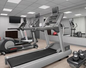Fitness center with treadmills, elliptical machines, dumbbells, wall mirrors and a red exercise ball at Courtyard By Marriott Dothan.