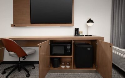 Guest room work area with wall-mounted television, wooden desk, office chair, microwave and mini refrigerator at Courtyard By Marriott Dothan.
