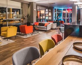 Hotel lounge and bar seating with colourful armchairs, sofas, pendant lights and a long communal table at Novotel Lima San Isidro.
