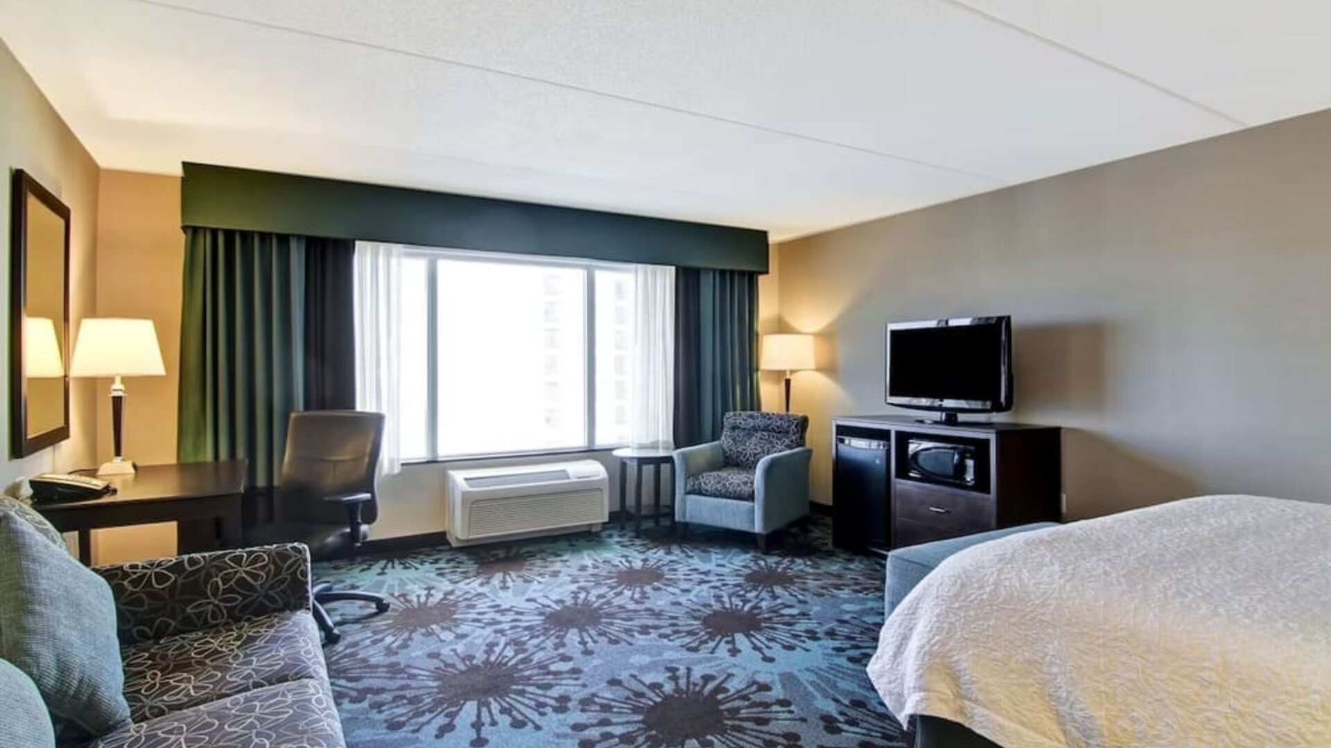 Day use room with TV, work desk and lounge area at Hampton Inn By Hilton Toronto Airport Corporate Centre.