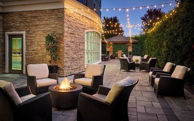 Outdoor patio with lounge seating and fireplace  at Staybridge Suites Oakville-Burlington.
