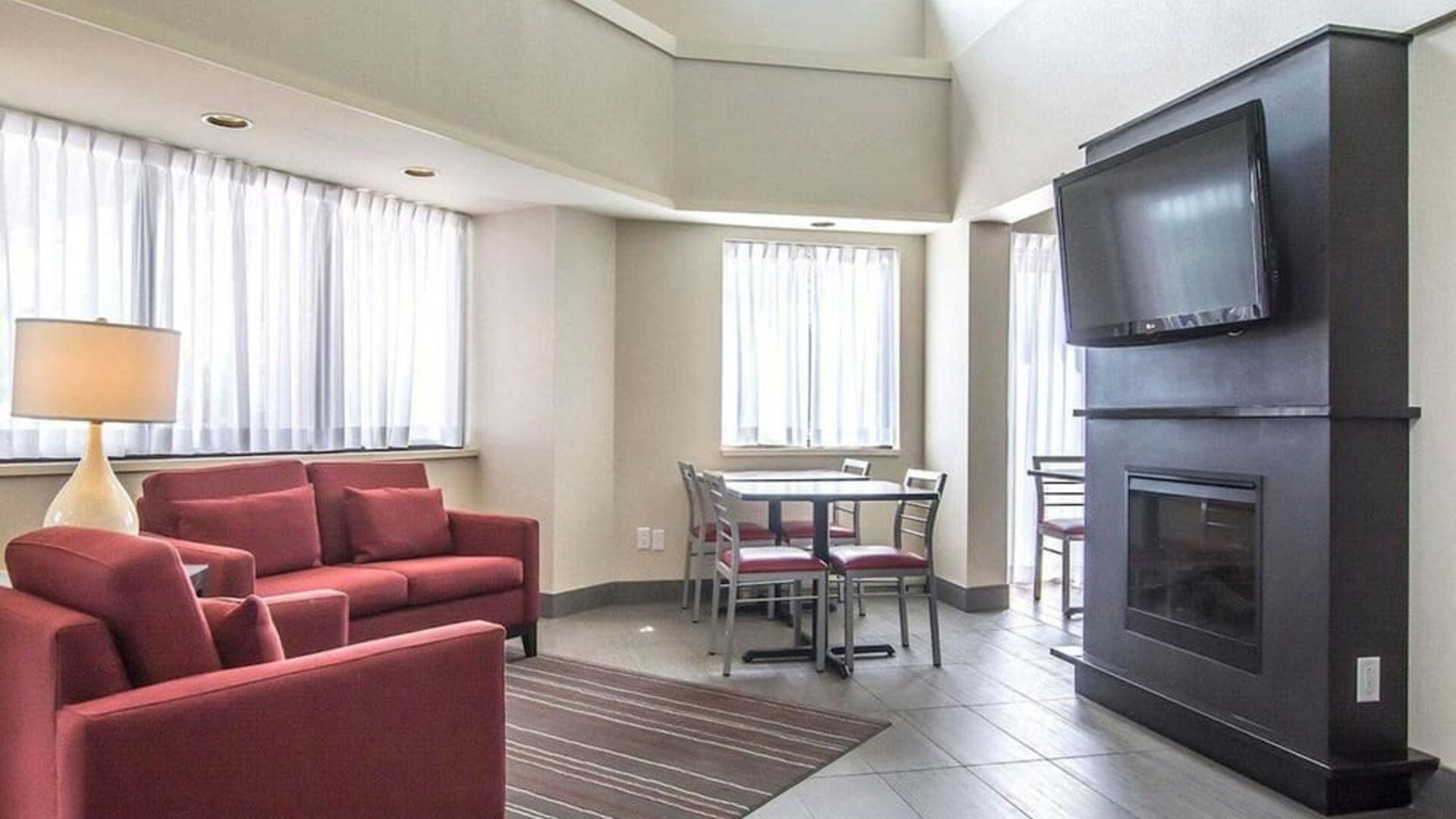 Lobby lounge with comfortable seating, TV screen and fireplace at Comfort Inn Alma.