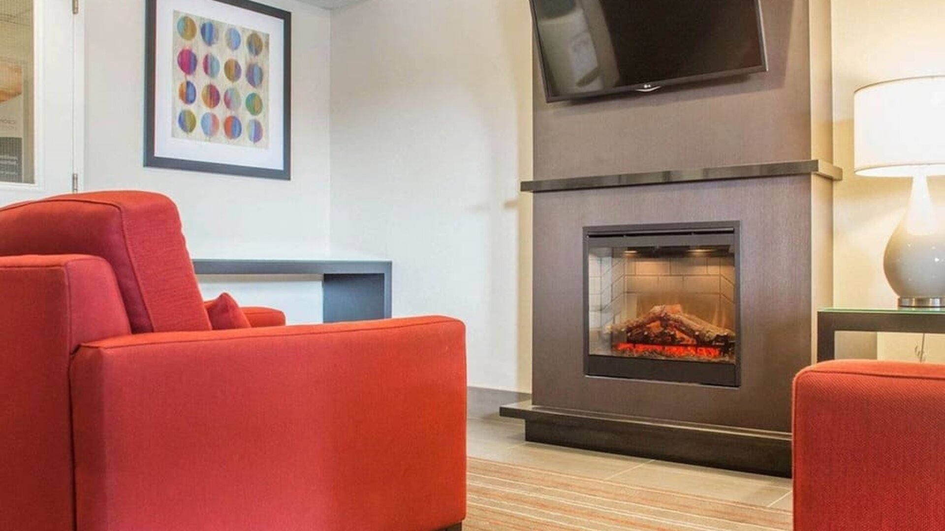Lobby lounge with TV screen and fireplace at Comfort Inn Brantford.