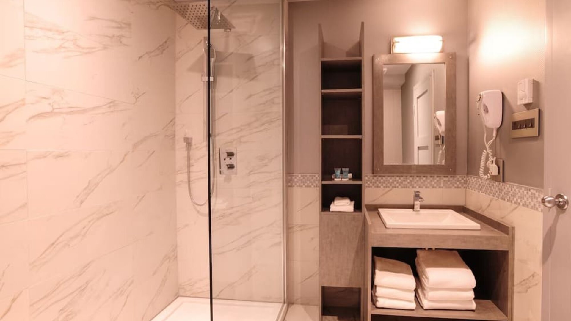 Guest bathroom with shower and free toiletries at Le Chabrol Hotel Et Suites.