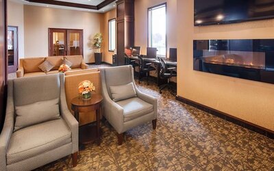 Comfortable lobby lounge with fireplace and workspace with computers, printer and ergonomic chairs at Best Western Plus Winnipeg Airport.