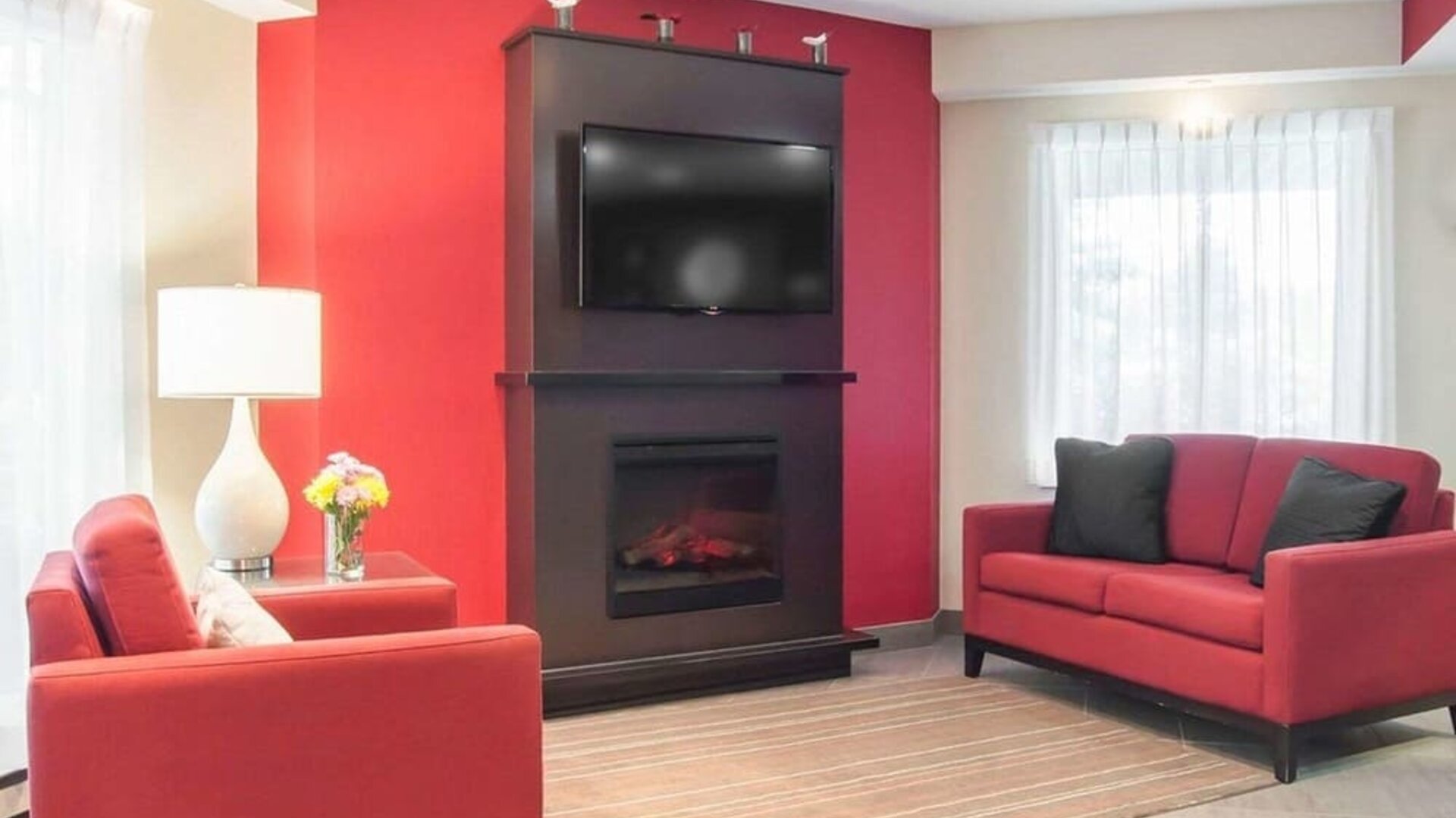 Lobby lounge with TV screen and fireplace at Comfort Inn Fredericton.