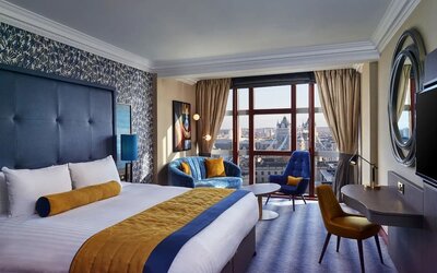 Day use room with work desk, lounge area and floor to ceiling window at Leonardo Royal Hotel London City.