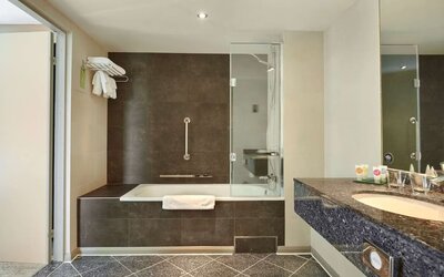 Guest bathroom with combined tub and shower at Hyatt Place London Heathrow Airport. 