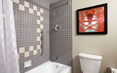 Guest bathroom with shower and tub at Embassy Suites By Hilton San Francisco Airport Waterfront.