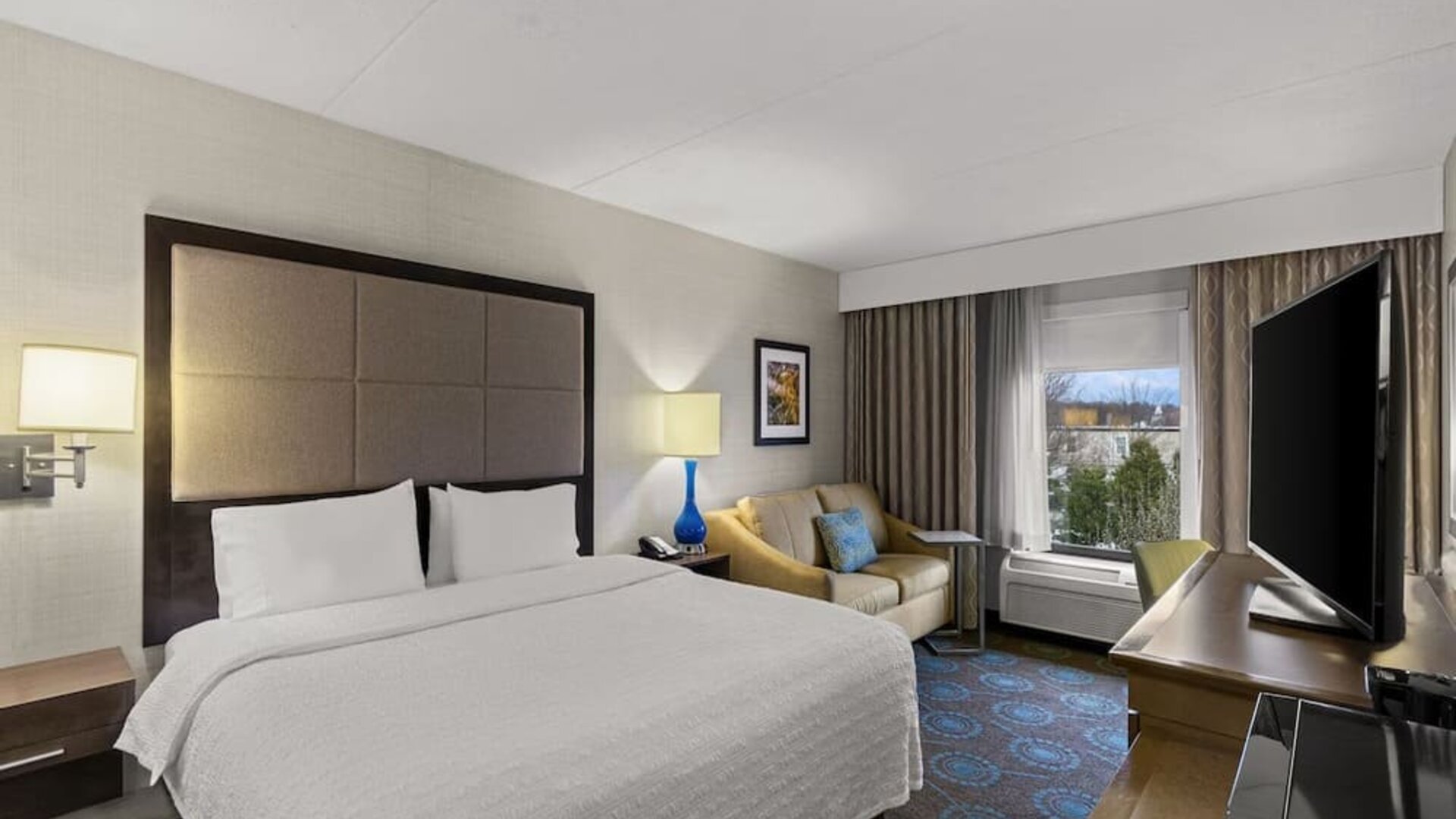 Comfortable king room with sofa and work desk at Hampton Inn Bloomington.