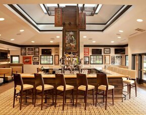 Sonesta Atlanta Airport South’s bar has numerous televisions on the wall, tall bar stools and booth seating, and a broad range of beverages.