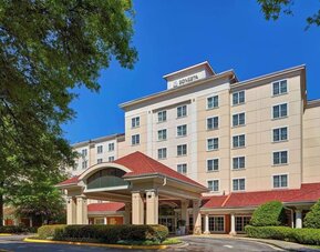 Sonesta Atlanta Airport South’s exterior features a covered entrance, well-kept greenery, and stylish red roof tiles.