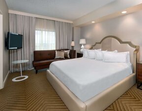 Comfortable king size bed with living area at Hilton Charlotte Airport.
