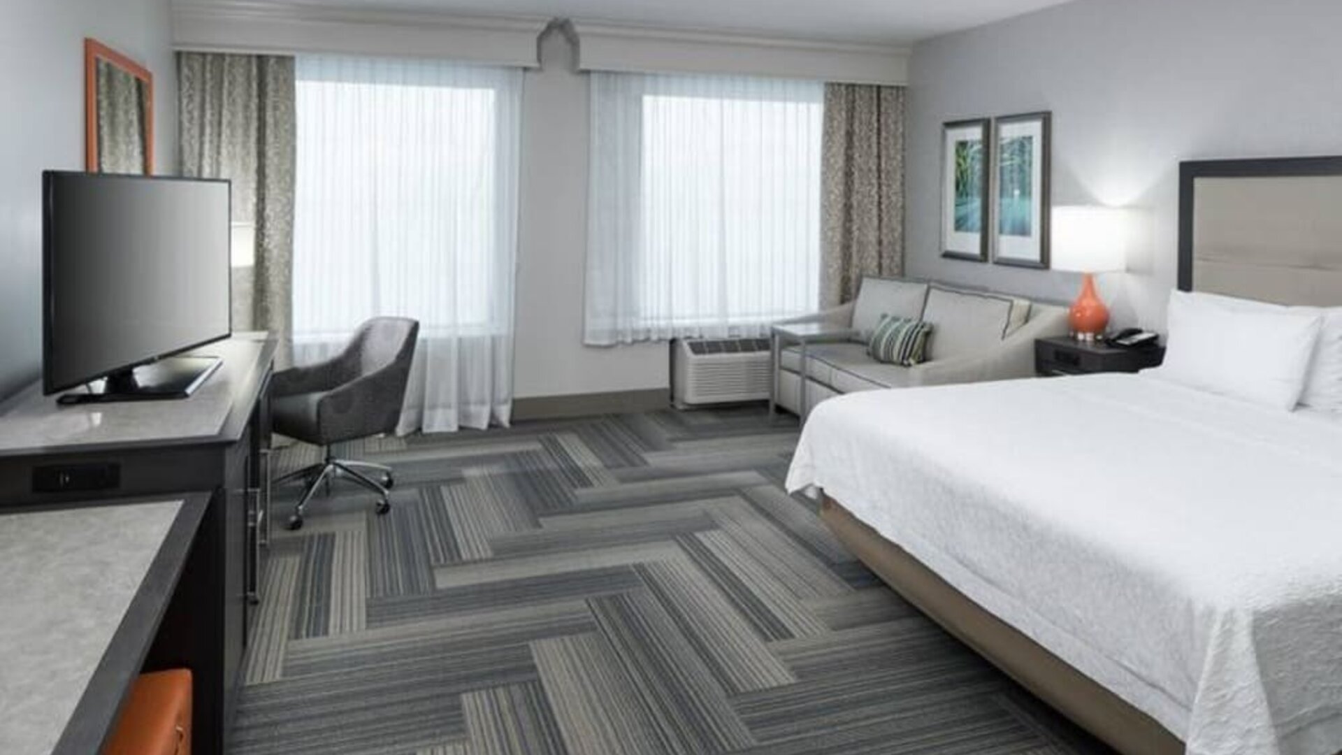 Spacious king bed room with work desk and sofa at Hampton Inn & Suites By Hilton Atlanta Perimeter Dunwoody.
