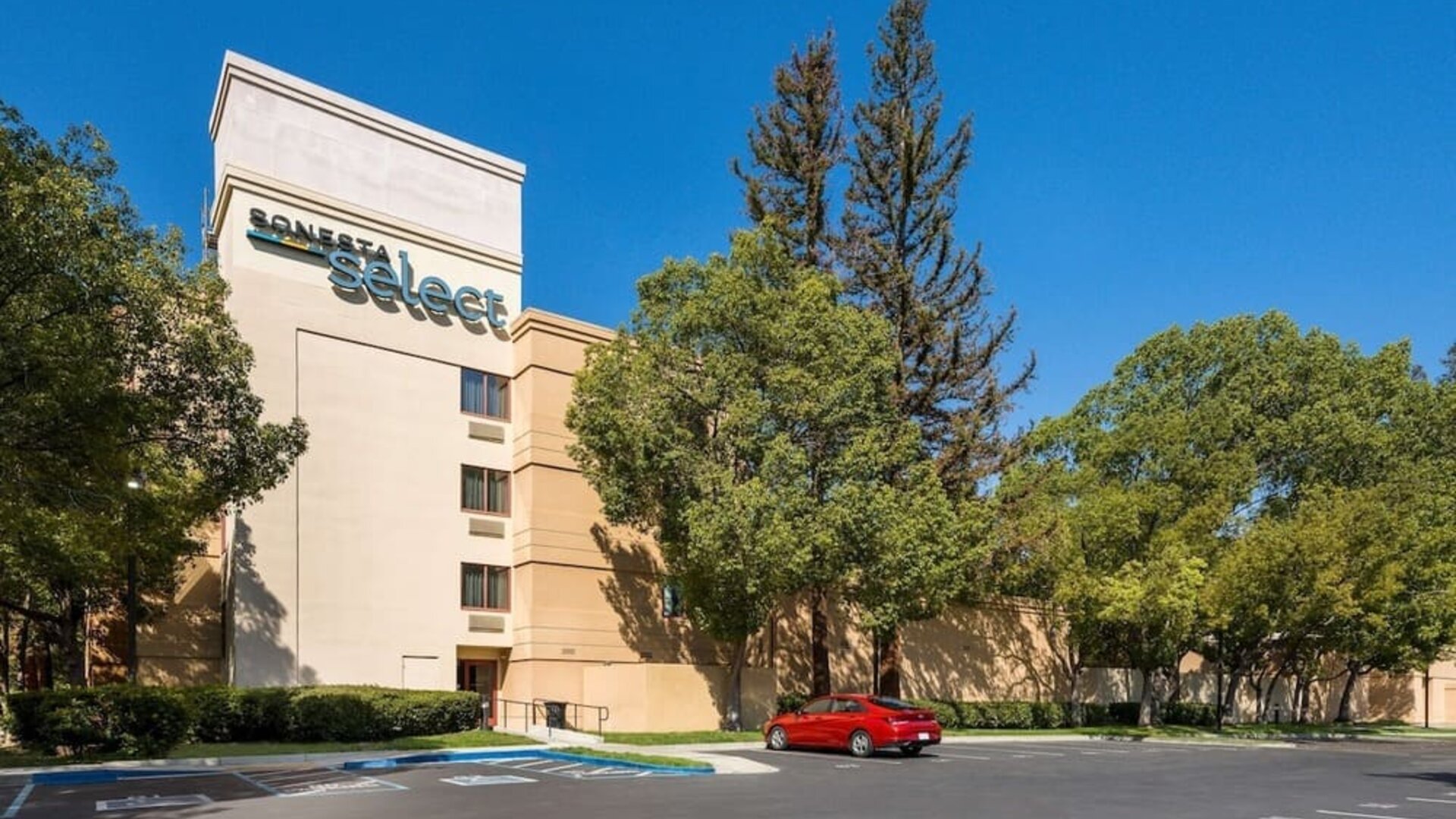 Hotel exterior and parking area at Sonesta Select San Jose Airport.