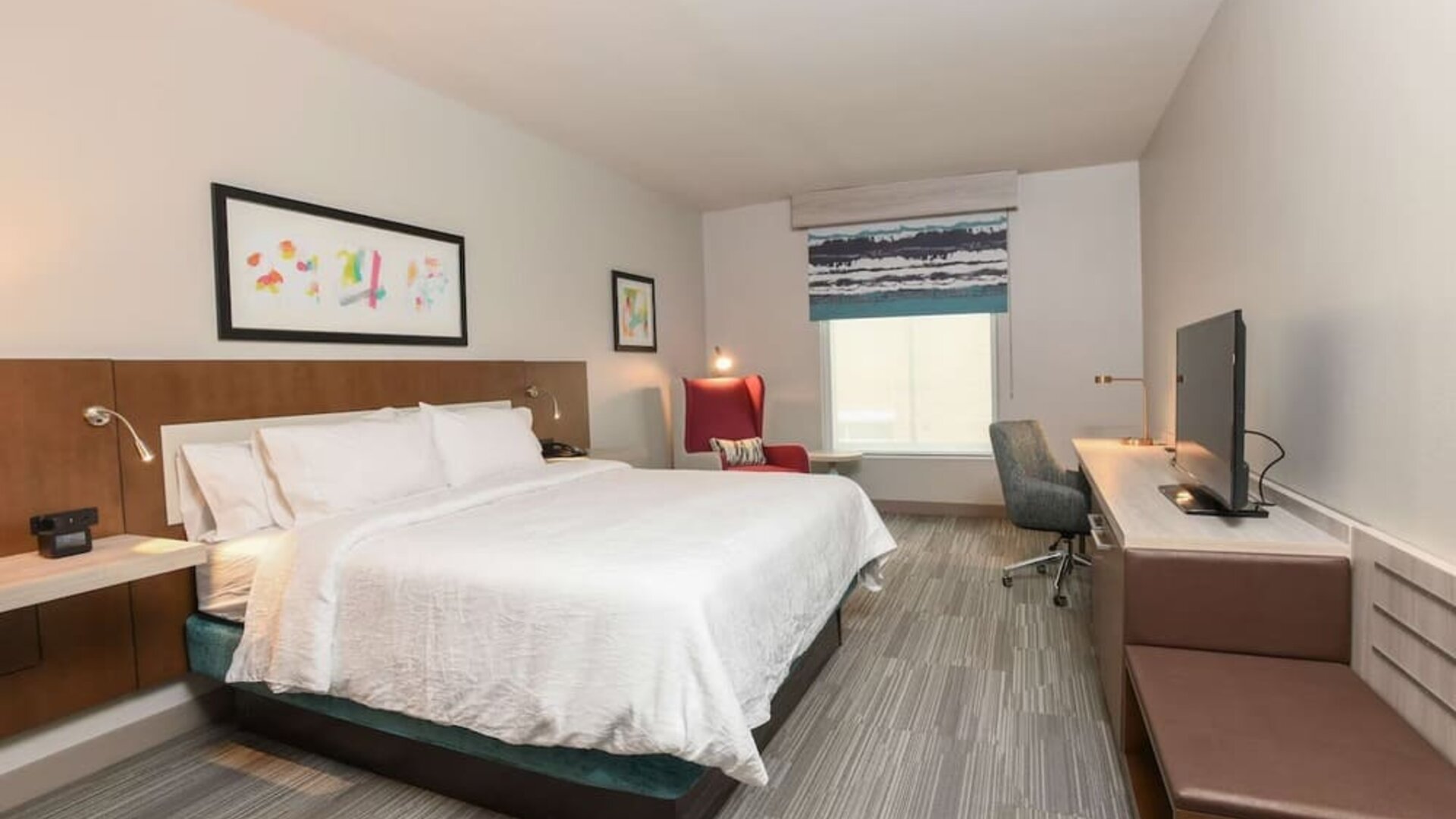 Bright and spacious day use room with king bed, work desk and TV screen at Hilton Garden Inn Cincinnati Midtown.