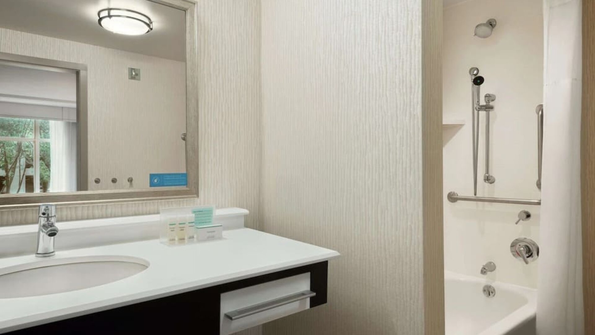 Private guest bathroom with combined shower and tub at Hampton Inn & Suites Rosemont Chicago O'Hare.