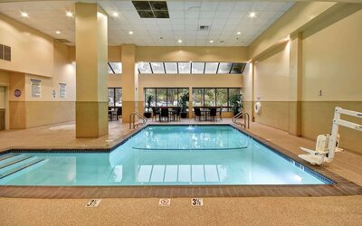 Relaxing indoor pool with seating area at Embassy Suites By Hilton Santa Clara Silicon Valley.