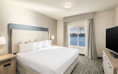 King bed with TV and a view of the Blue Lagoon at Homewood Suites By Hilton Miami Airport-Blue Lagoon.