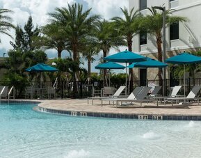 Outdoor pool with lounge chairs at Home2 Suites By Hilton Cape Canaveral Cruise Port.