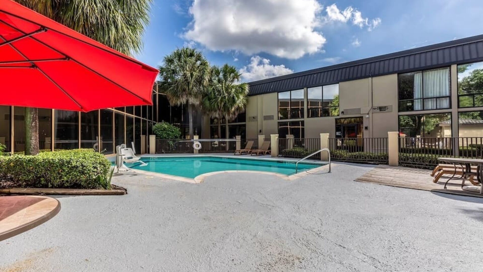 Hotel patio with lounge chairs and outdoor pool at Red Roof PLUS+ & Suites Houston - IAH Airport SW.