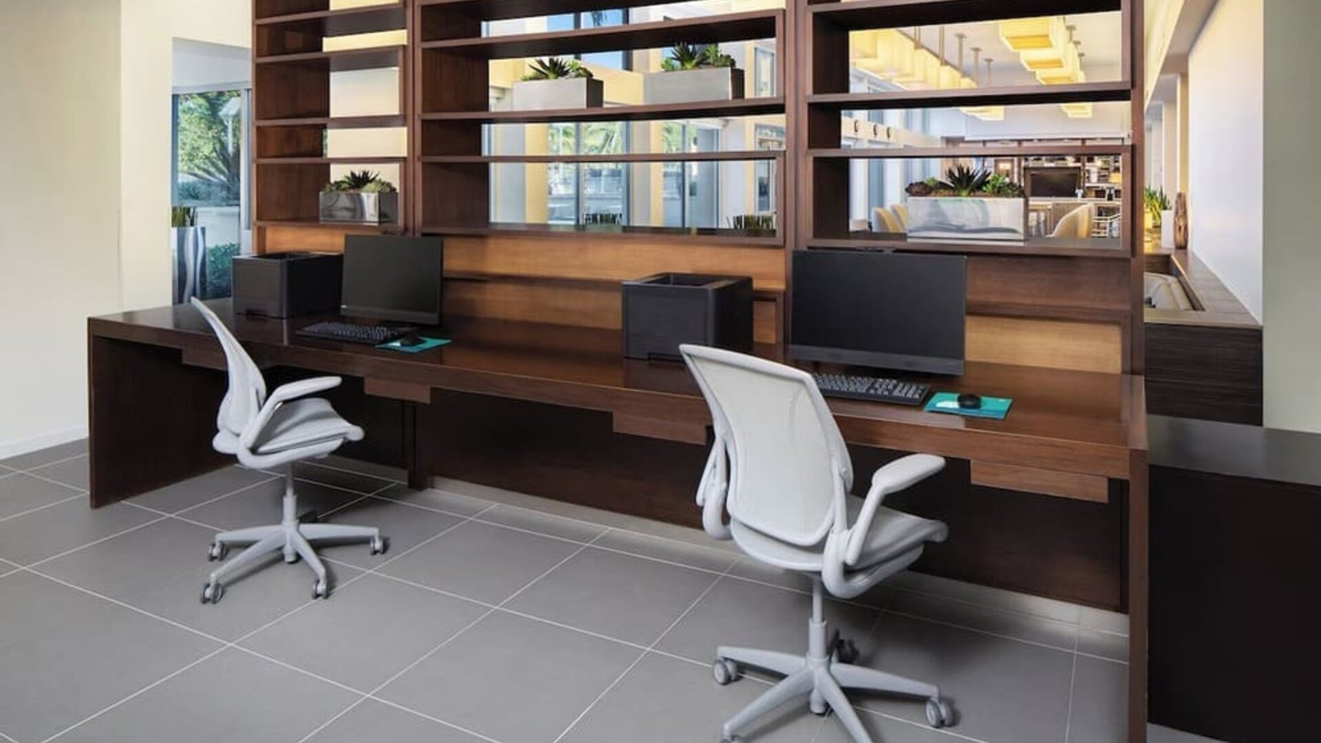 Business center with computers, printer and ergonomic chairs at Element Miami International Airport.