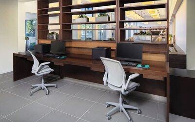 Business center with computers, printer and ergonomic chairs at Element Miami International Airport.