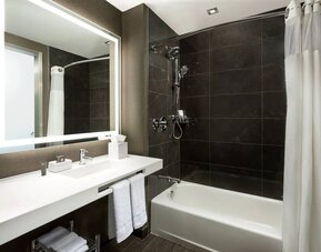 Private guest bathroom with combined shower and tub at AC Hotel New York Times Square.