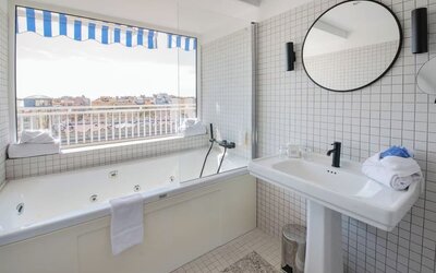 Guest bathroom with tub and natural light at Splendid Hotel & Spa Nice.