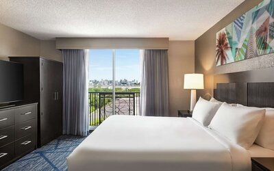 Day use room with king bed, balcony, TV screen and private bathroom at Embassy Suites By Hilton Miami - International Airport.