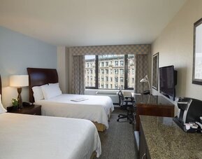 Guest room with two beds and a functional workspace at Hilton Garden Inn Tribeca.