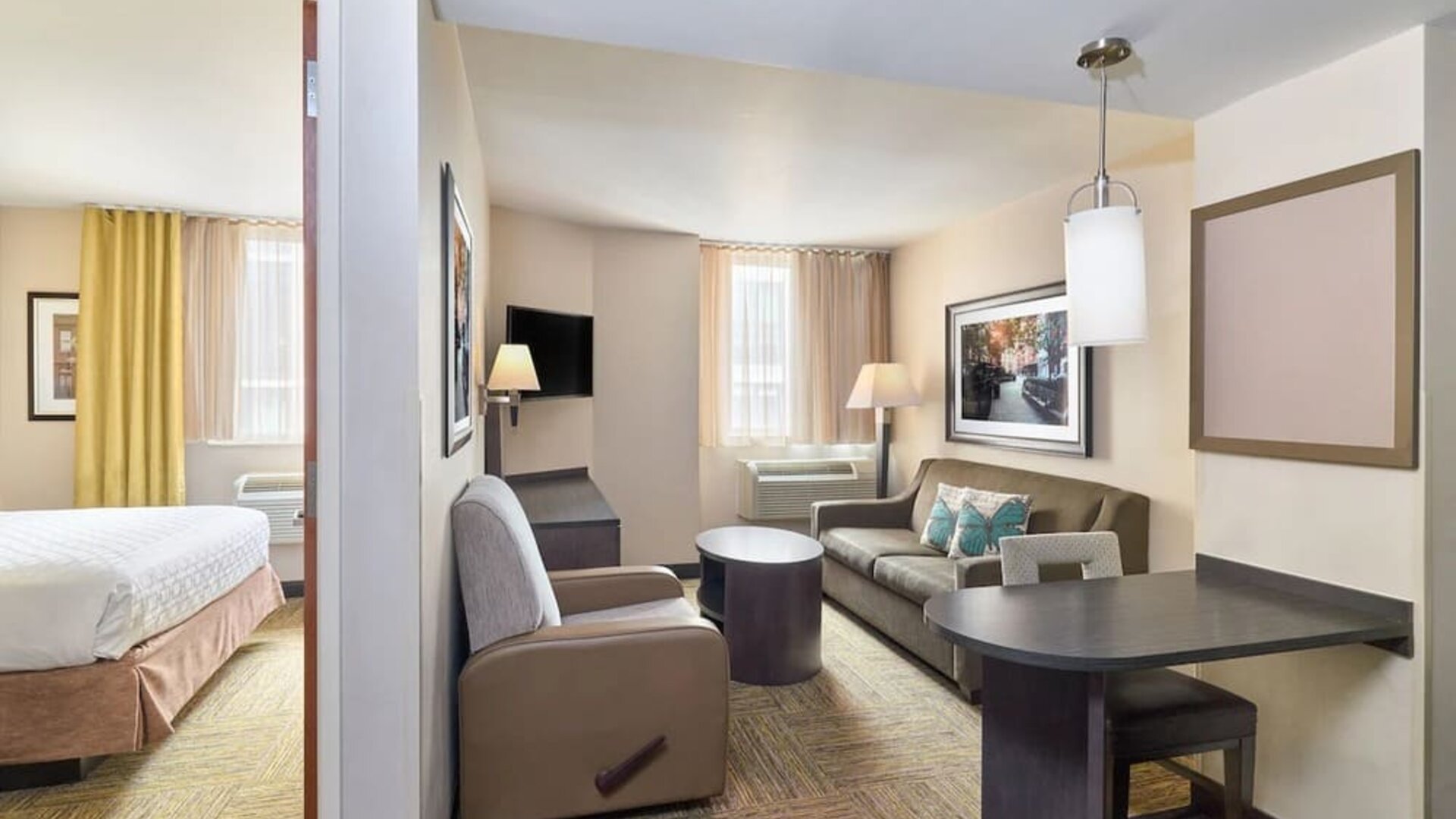 Day room at Candlewood Suites Times Square, with workspace, couch and large window.