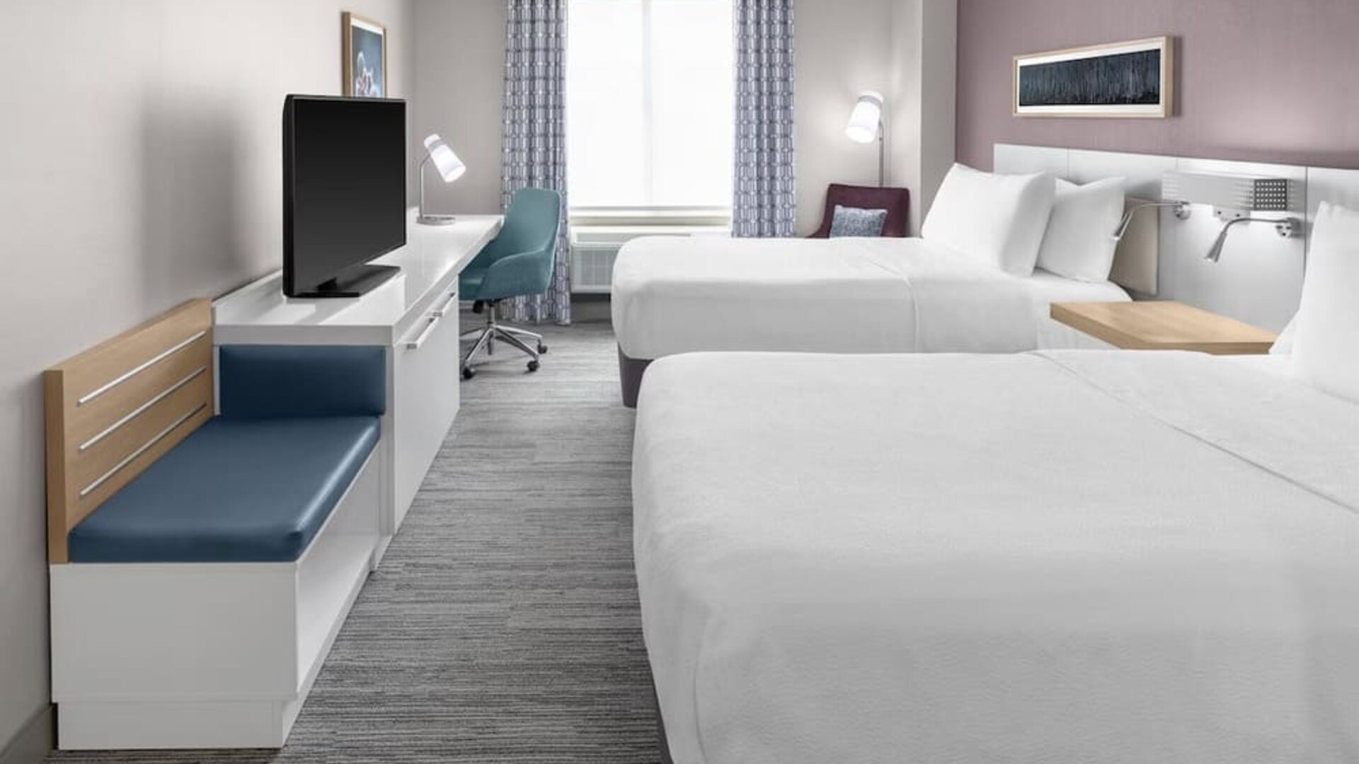 Spacious guest room at Hilton Garden Inn Queens/JFK Airport with two beds, desk, seating, and window.