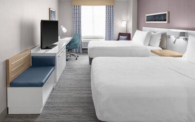 Spacious guest room at Hilton Garden Inn Queens/JFK Airport with two beds, desk, seating, and window.