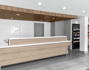 Reception area at Hilton Garden Inn Queens/JFK Airport with wood desk, and a white counter.